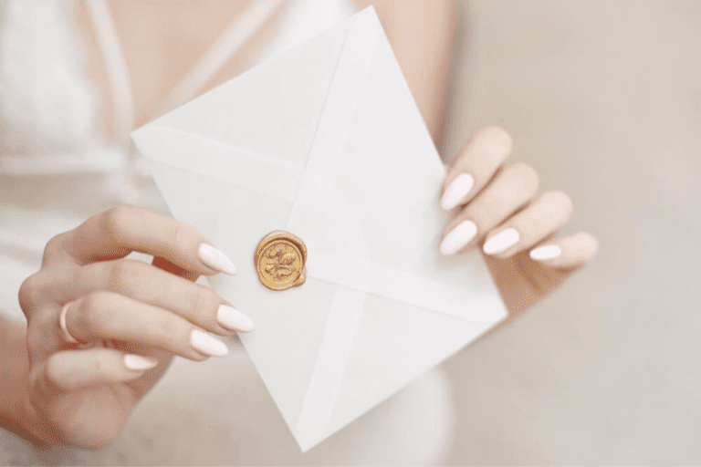 kobiece dłonie trzymające białą kopertę z zaproszeniem ślubnym