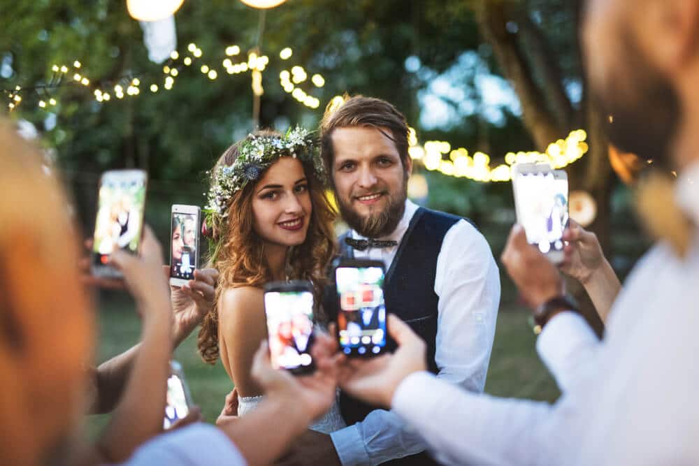 goście weselni robią zdjęcia telefonem parze młodej